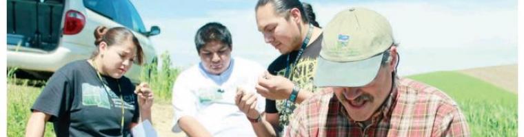 Students and teachers examine soil samples in the field